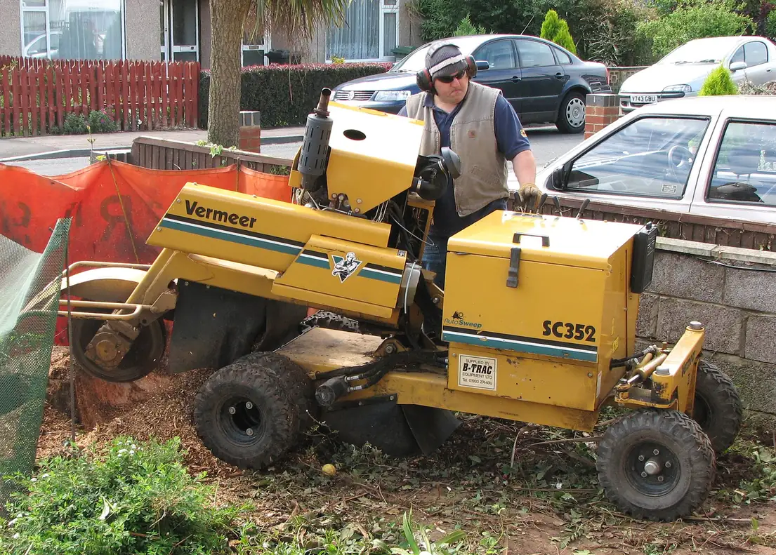 A wheeled stump grinder parked beside a work area